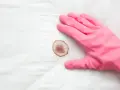 Guanto rosa pronto a rimuovere macchie di sangue da un materasso.