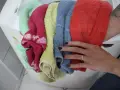 Mani che prendono un mucchio di lavatrice colorati: rosso, blu, giallo, rosa e verde menta.