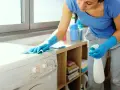 Donna con guanti blu pulisce la lavatrice, pronta per scoprire come pulire la resistenza della lavatrice.