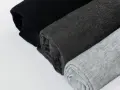 Come lavare un capo bianco e nero in lavatrice: tessuti arrotolati in nero, grigio scuro e grigio chiaro.
