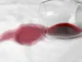 Un bicchiere rovesciato ha creato delle macchie rosse su un tessuto bianco. La candeggina potrebbe essere la soluzione per rimuoverle.