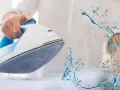Ferro da stiro con spruzzo d'acqua. L'acqua per ferro da stiro aiuta a eliminare le pieghe dai tessuti.