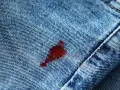 Macchia rossa su jeans blu. Attenzione, l'acqua ossigenata macchia i vestiti, lasciando segni indelebili.