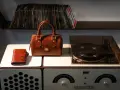 Borsa in pelle marrone, portafoglio e giradischi vintage. Un set per chi ama la musica e lo stile classico, pronto per essere pulito.