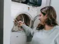 Donna carica la lavatrice, pronta a smacchiare tessuti sintetici con cura.