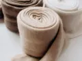 Rotoli di morbido cashmere in tonalità naturali, pronti per il lavaggio e la cura.