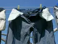 Pantaloni in denim appesi ad asciugare al sole, con tasche interne visibili.