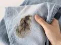 Mano che mostra un jeans macchiato, pronto per essere smacchiato.
