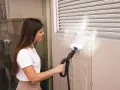 Donna pulisce una parete esterna con una **vaporella Polti**, dimostrando la **manutenzione** efficace contro lo sporco.