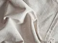 Tessuto grezzo color crema, pieghe morbide. Scopri come ammorbidire un tessuto sintetico per un tocco più piacevole.