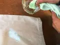Mani che tamponano macchie di colore su tessuto con un panno umido.