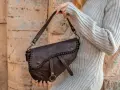 Donna con borsa a tracolla in pelle marrone, con cuciture decorative. Scopri come ammorbidire la pelle delle borse per un look sempre perfetto.