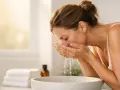 Donna si lava il viso con acqua, un gesto quotidiano per pulire e come smacchiare la pelle.
