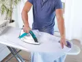 Uomo stira camicia, ma non esce vapore dal ferro da stiro con caldaia. La stiratura è difficile.