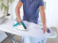 Uomo stira una camicia. Impara come pulire la piastra del ferro da stiro per risultati perfetti.