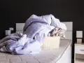 Cesto di biancheria da letto accartocciata, pronto per il bucato. Un promemoria per imparare come smacchiare il lino e far brillare le lenzuola.
