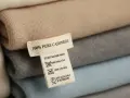 Pile di maglioni in cashmere. L'etichetta indica "100% PURE CASHMERE" e suggerisce il lavaggio a secco per preservare la morbidezza.