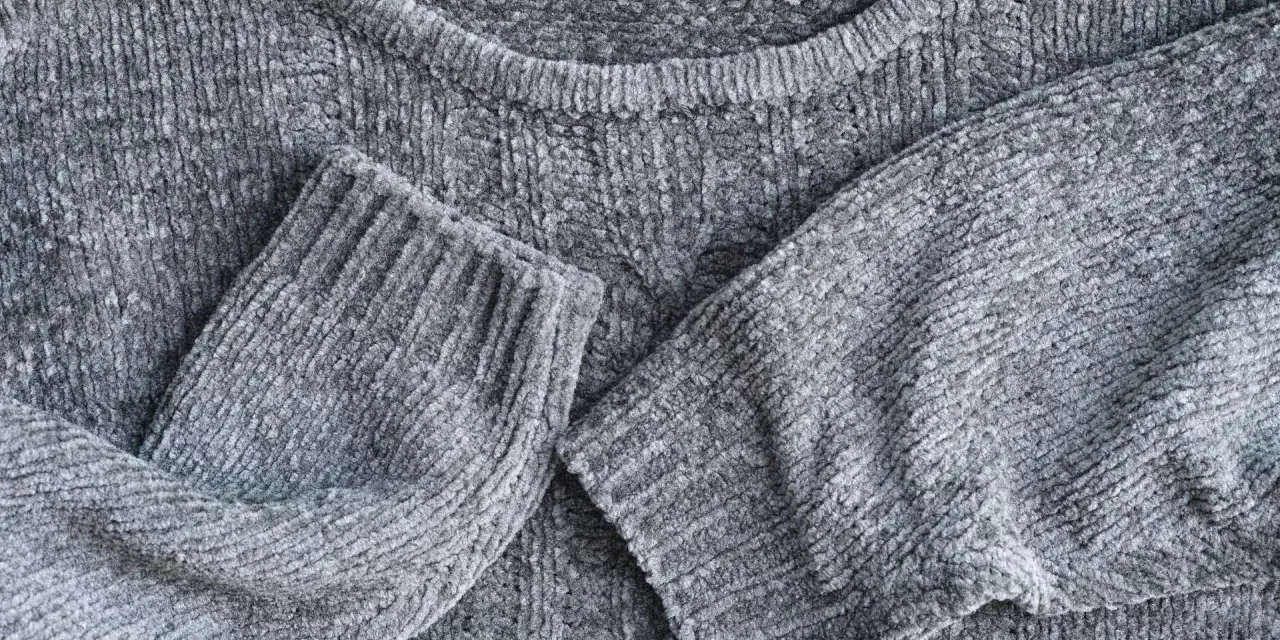 Maglione grigio in morbida lana, con maniche piegate.