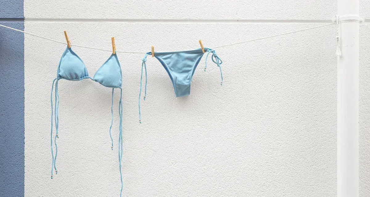 Costume da bagno azzurro appeso ad asciugare. Facile da lavare in lavatrice, pronto per la prossima avventura al mare.
