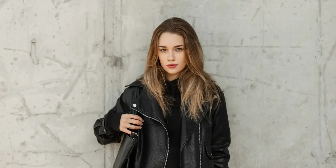 Ragazza con giubbotto di pelle nera, pronta per lavare il giubbotto in lavatrice.