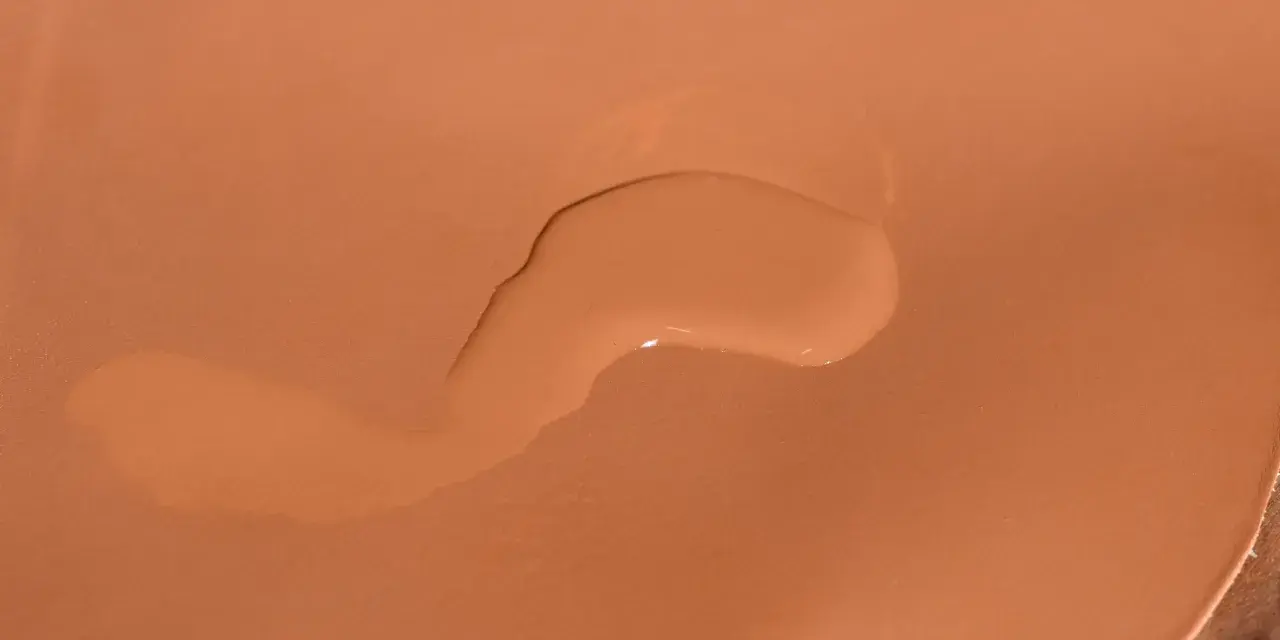 Una goccia d'acqua sola su una borsa di pelle color cuoio.