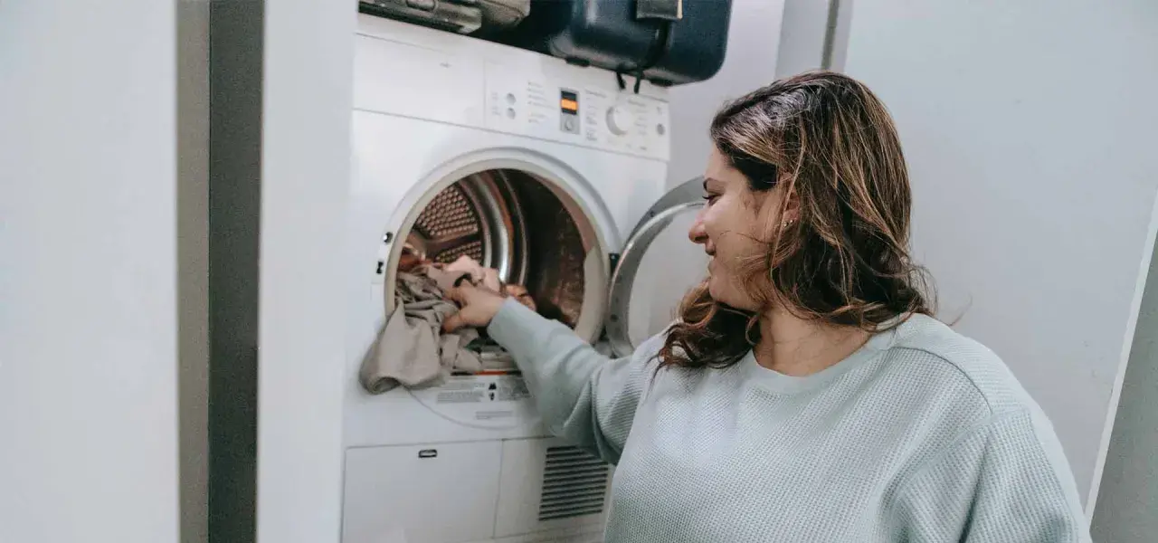 Donna carica la lavatrice, pronta a smacchiare tessuti sintetici con cura.