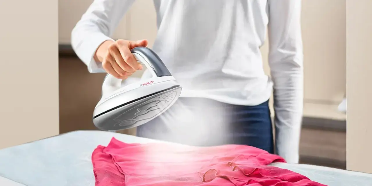 Donna stira un abito rosa con il ferro da stiro Polti Kalstop, creando vapore.