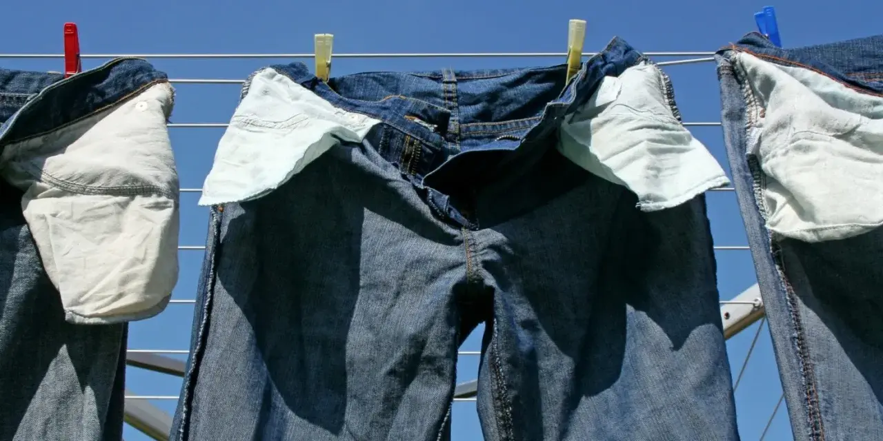 Pantaloni in denim appesi ad asciugare al sole, con tasche interne visibili.