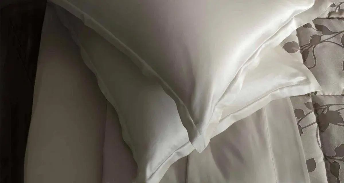 Federa di seta bianca, con un lenzuolo sottostante. Scopri come lavare la seta ingiallita per mantenerla luminosa.