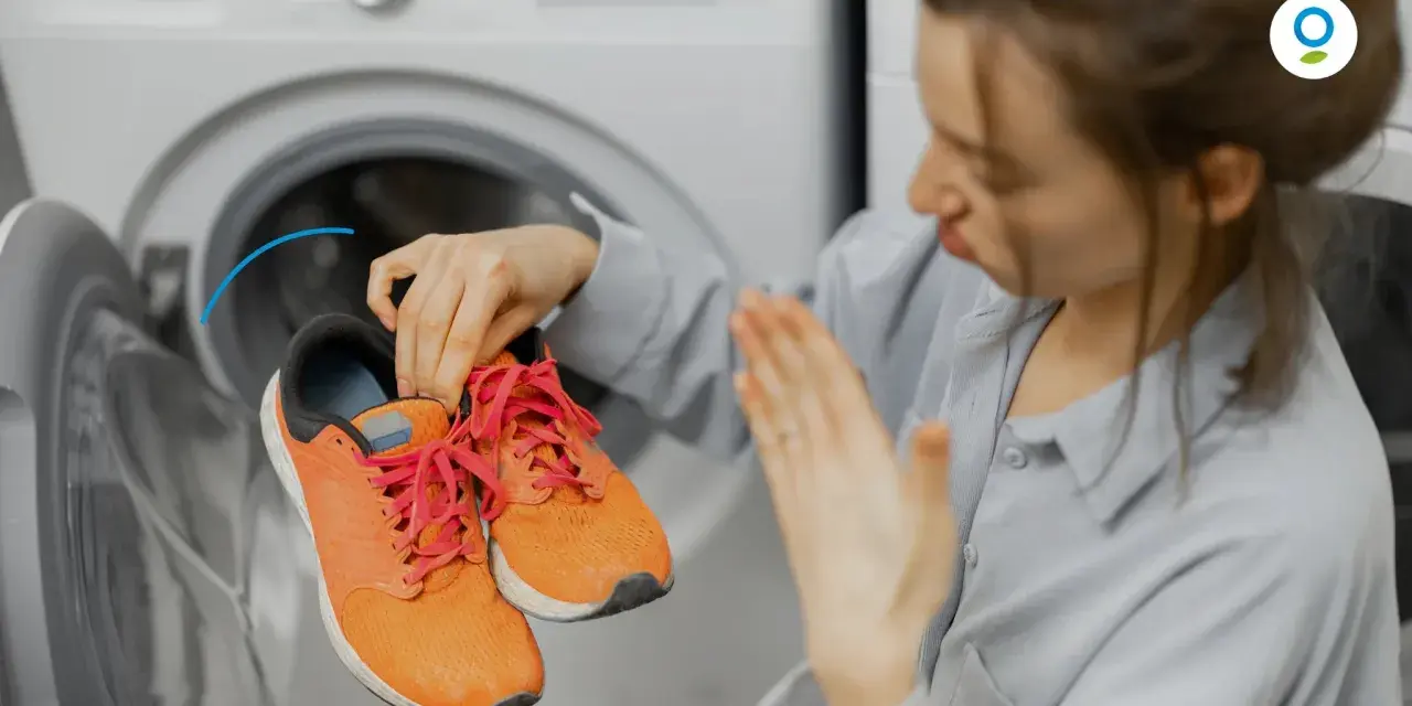 Donna con scarpe arancioni davanti a una lavatrice. Scopri come fare un lavaggio a vuoto per pulire la lavatrice.