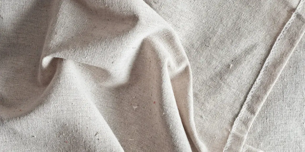 Tessuto grezzo color crema, pieghe morbide. Scopri come ammorbidire un tessuto sintetico per un tocco più piacevole.