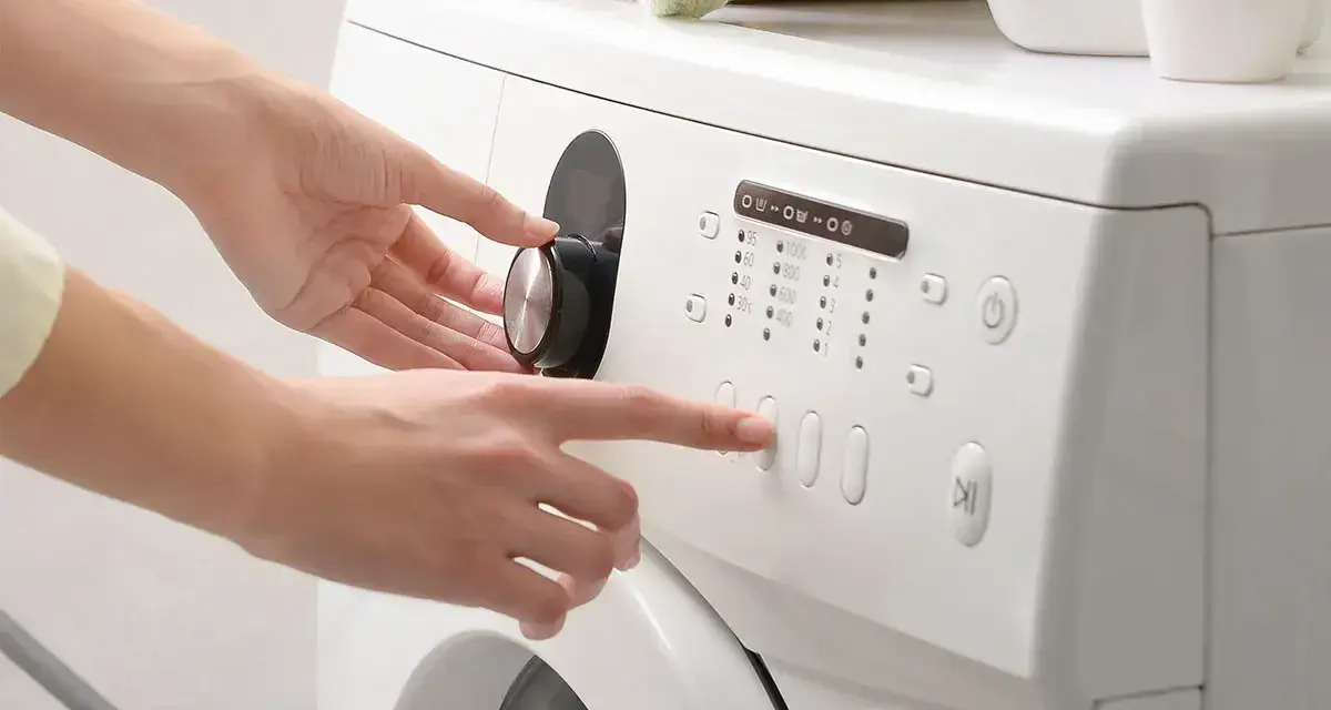 Mani impostano la lavatrice, scegliendo il programma e la velocità di rotazione per capire quanto dura la centrifuga della lavatrice.