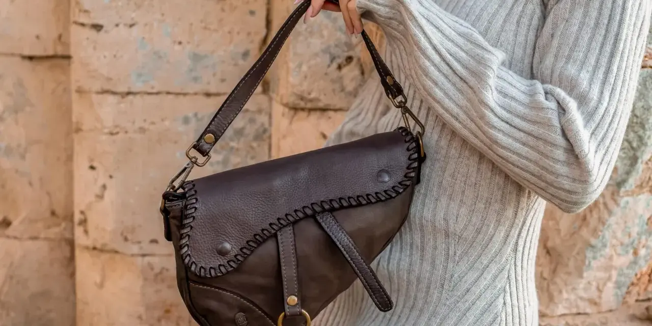 Donna con borsa a tracolla in pelle marrone, con cuciture decorative. Scopri come ammorbidire la pelle delle borse per un look sempre perfetto.