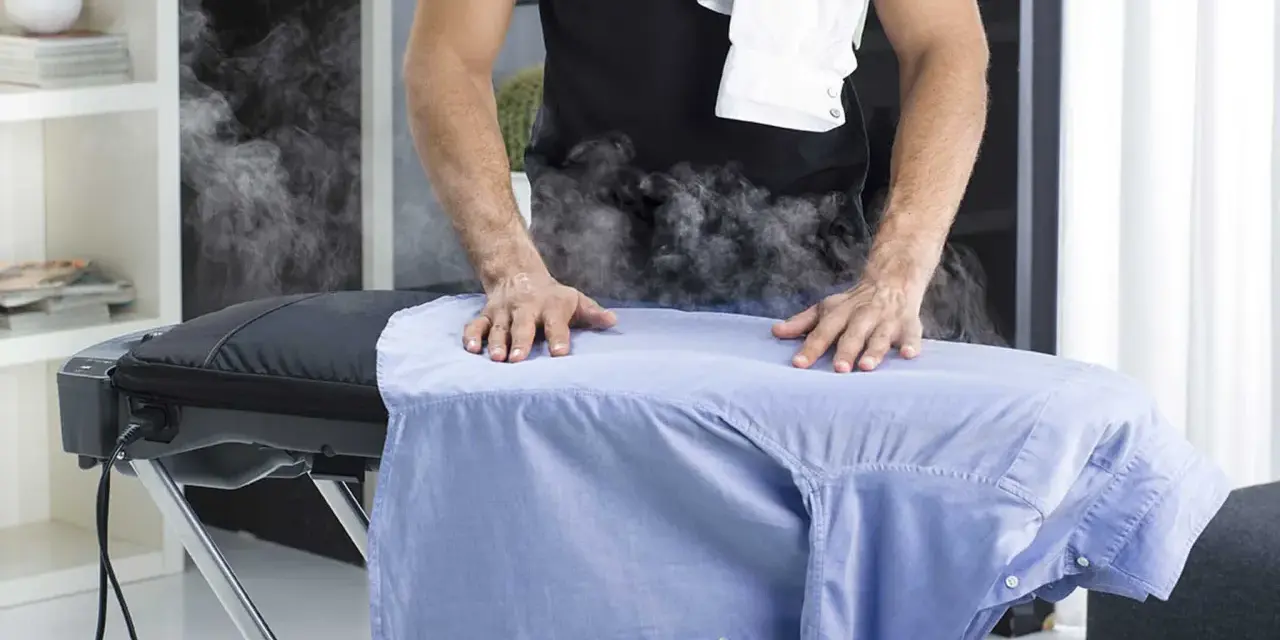 Uomo stira camicia azzurra con vapore. Per un lavaggio misto in lavatrice, quanti gradi?