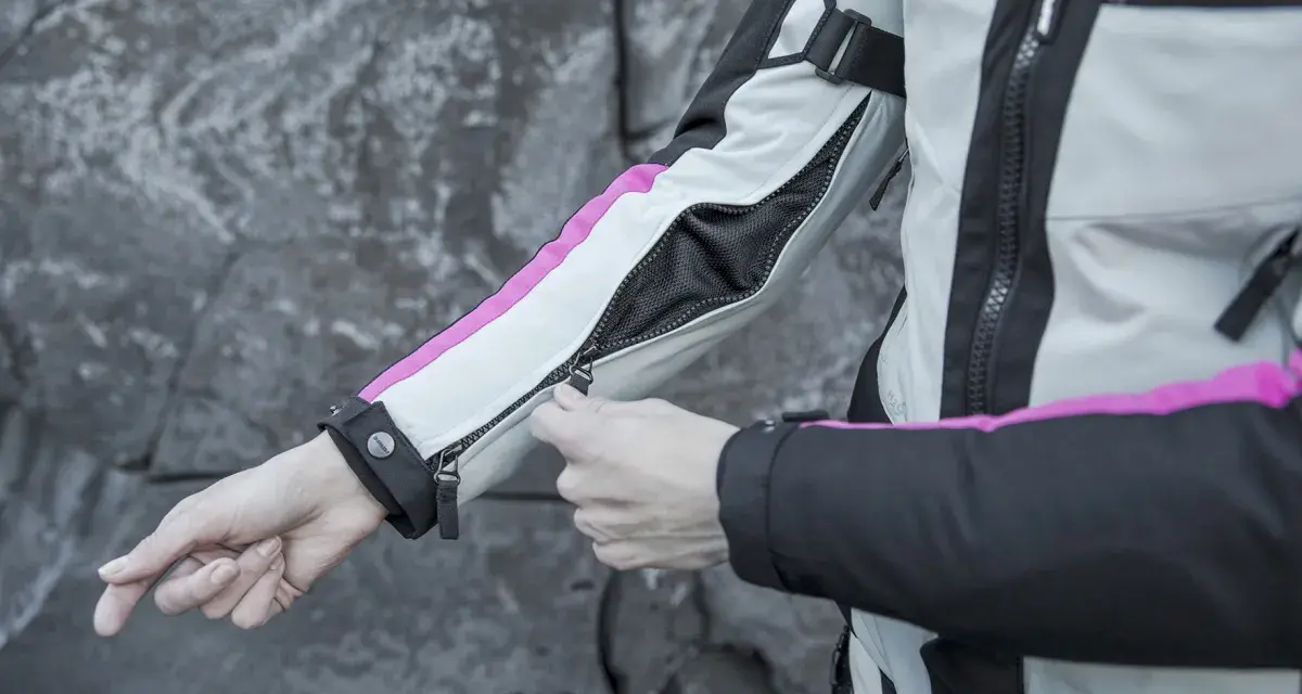 Mani che chiudono la zip di una giacca da moto, pronta per essere lavata in lavatrice.