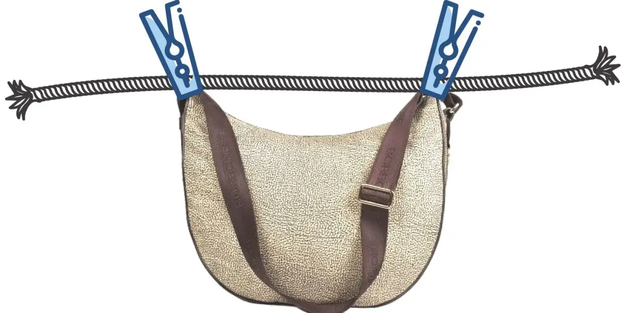 Borsa in tessuto beige con tracolla marrone appesa ad asciugare con mollette. Guida su come pulire una borsa in tessuto.