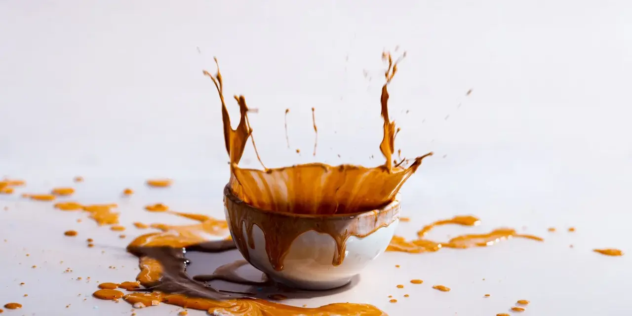 Schizzo di liquido marrone da una ciotola, creando macchie marroni sui vestiti dopo lavaggio in lavatrice.
