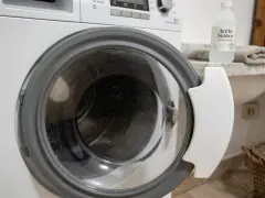 Dettaglio di una lavatrice con oblò aperto, pronto per un ciclo di pulizia con aceto bianco, per una vita media ottimale dell'elettrodomestico.