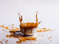 Schizzo di liquido marrone da una ciotola, creando macchie marroni sui vestiti dopo lavaggio in lavatrice.
