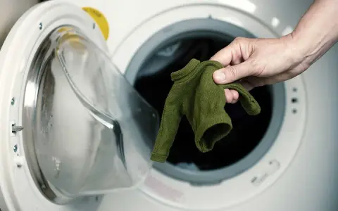 Maglione di viscosa ristretta, rimedi per recuperarlo. Mano che estrae il capo dalla lavatrice.