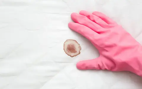 Guanto rosa pronto a rimuovere macchie di sangue da un materasso.
