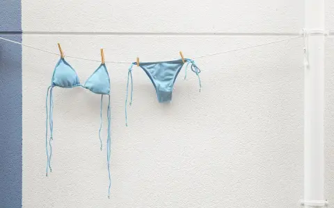 Costume da bagno azzurro appeso ad asciugare. Facile da lavare in lavatrice, pronto per la prossima avventura al mare.