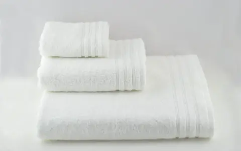 Tre soffici asciugamani bianchi impilati. Perfetti per imparare come smacchiare asciugamani bianchi e mantenerli impeccabili.