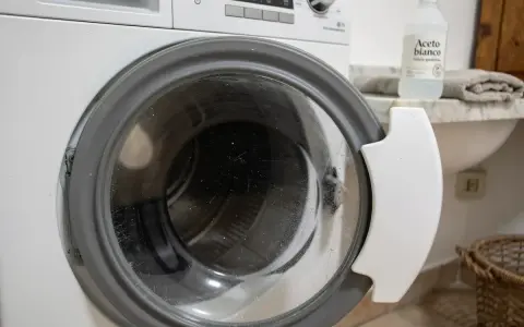 Dettaglio di una lavatrice con oblò aperto, pronto per un ciclo di pulizia con aceto bianco, per una vita media ottimale dell'elettrodomestico.