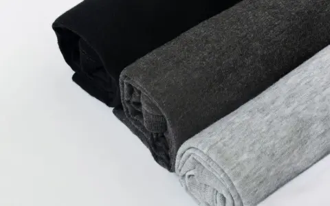 Come lavare un capo bianco e nero in lavatrice: tessuti arrotolati in nero, grigio scuro e grigio chiaro.
