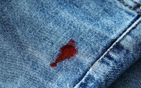 Macchia rossa su jeans blu. Attenzione, l'acqua ossigenata macchia i vestiti, lasciando segni indelebili.