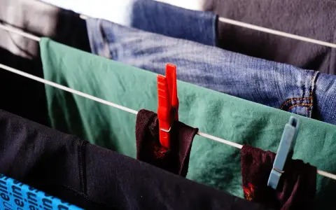 Panni stesi su uno stendibiancheria, con mollette rosse e azzurre. Un modo semplice per capire come strizzare i panni a mano.