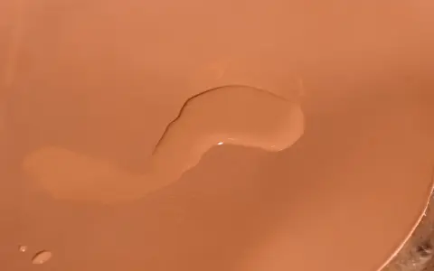 Una goccia d'acqua sola su una borsa di pelle color cuoio.