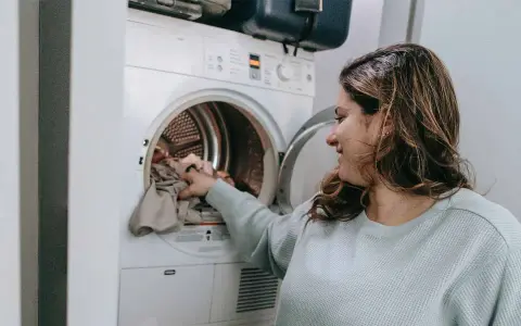 Donna carica la lavatrice, pronta a smacchiare tessuti sintetici con cura.