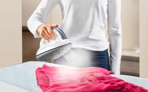 Donna stira un abito rosa con il ferro da stiro Polti Kalstop, creando vapore.